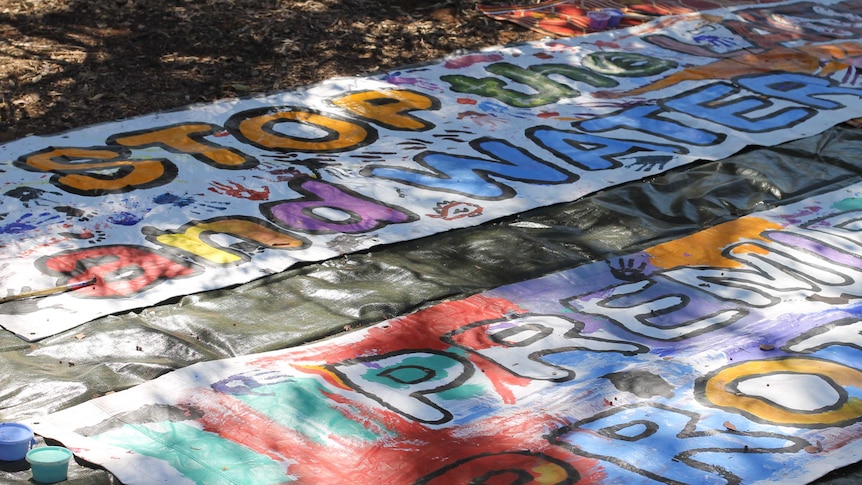 A banner with writing on it that says stop the land and water grab