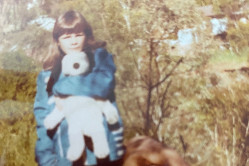 Nanette Vardy-Forth as a child, with a toy and a suitcase.