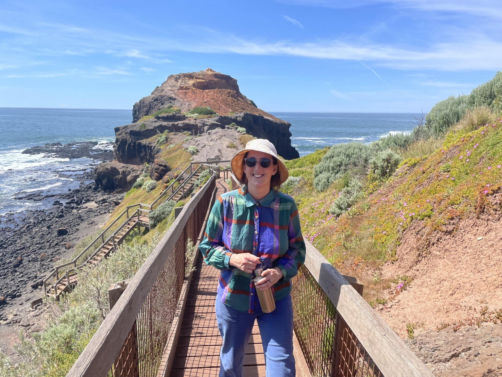 A woman standing on a walkway near the coast.