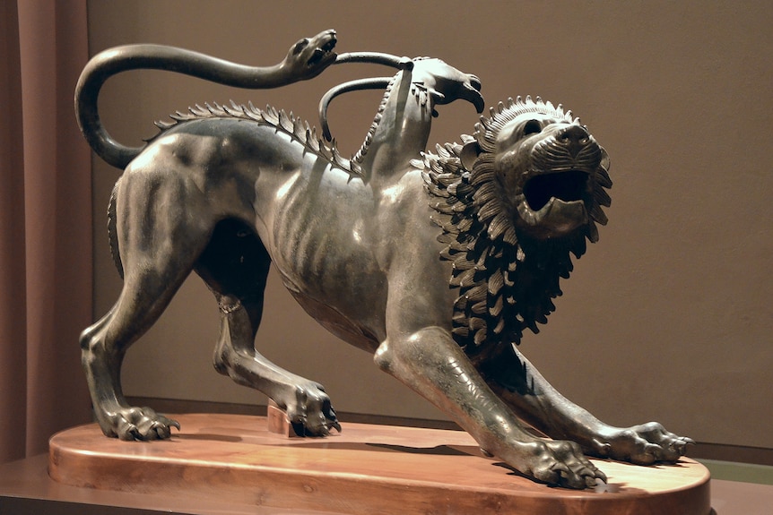 A bronze statue of a male lion with a horned goat head on its back and a snake as a tail, all three faces have their mouths open