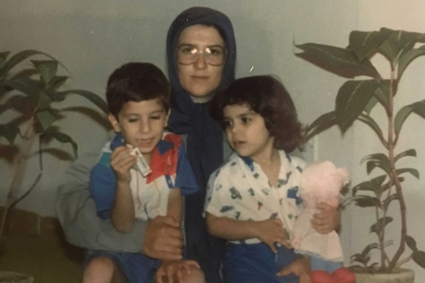 Archival photo of Katauon Najafi, in headscarf and glasses, sitting with two young children.