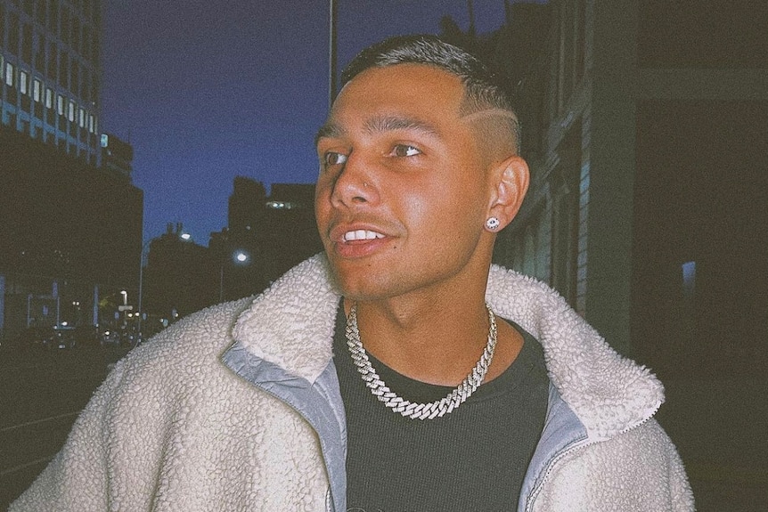 A young Aboriginal man wearing a jacket and a silver chain necklace