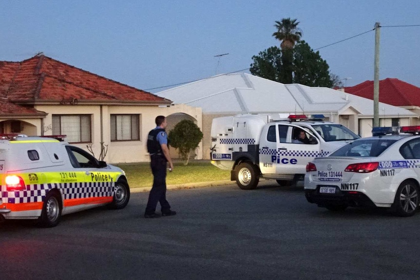 Three police cars and a policeman outside houses on a suburban street in Perth.