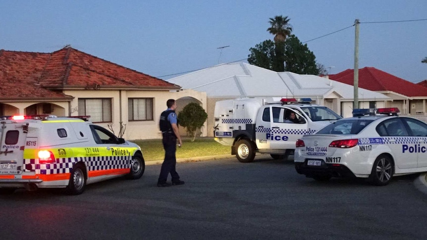 Three police cars and a policeman outside houses on a suburban street in Perth.