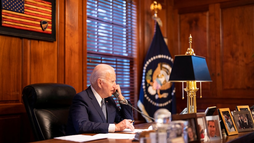 Joe Biden speaking on the phone at a desk in his home office. 