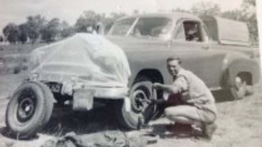black and white photo of man next to car