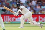India batsman Virat Kohli plays a cricket shot as an Australian fielder looks on.