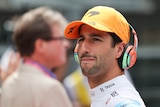Daniel Ricciardo wearing headphones while standing in the pit lane