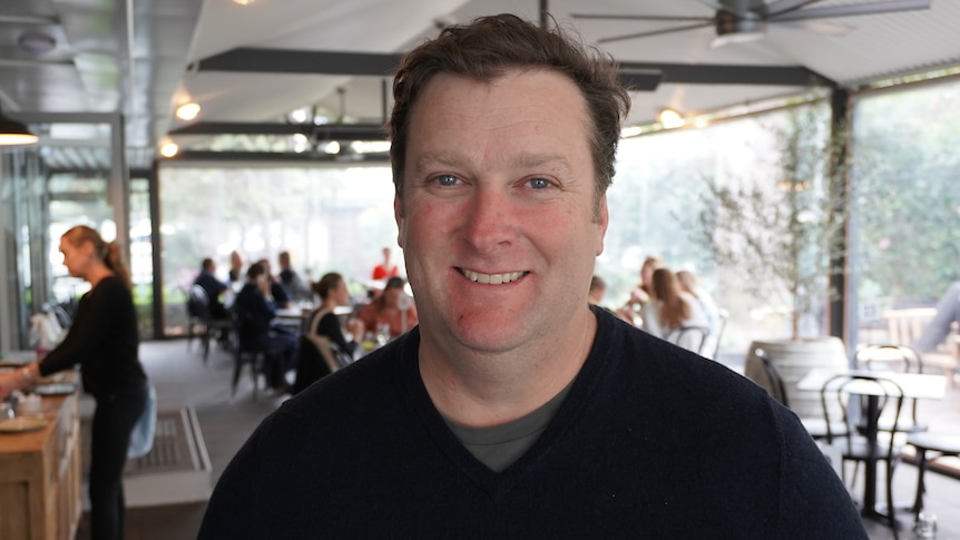 Man smiling, wearing a blue jumper