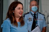 Queensland Premier Anastacia Palaszczuk smiles slightluy while wearing a sky blue dress. 