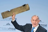 Israeli Prime Minister Benjamin Netanyahu holds a piece of a downed done.
