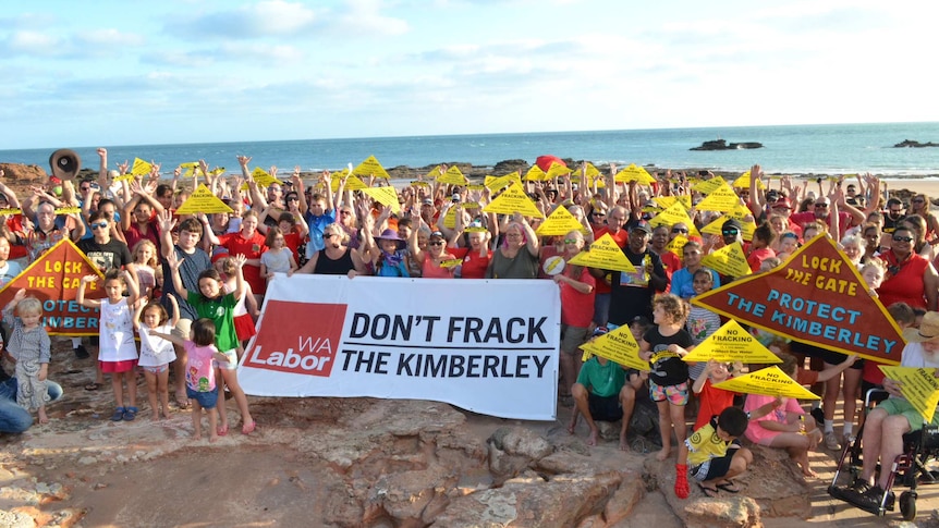 A wide shot of anti-fracking protestors carrying banners and placards at Broome’s Entrance Point beach.