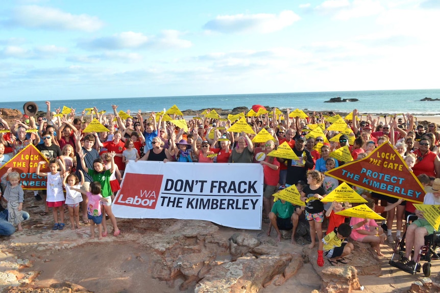 A wide shot of anti-fracking protestors carrying banners and placards at Broome’s Entrance Point beach.