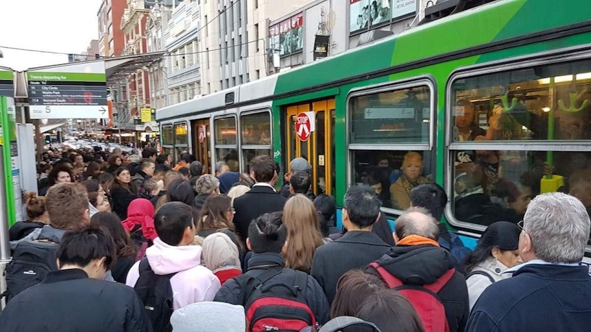 lots of people squeezing onto a crowded tram in melbourne
