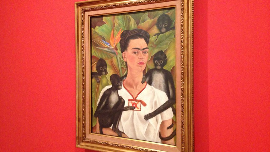 A framed portrait of Frida Kahlo in which she is surrounded by monkeys.