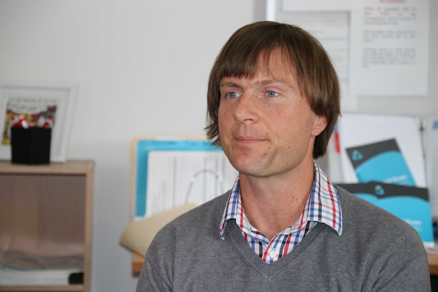 Ben Bartl from the Tenants Union of Tasmania sits in an office.