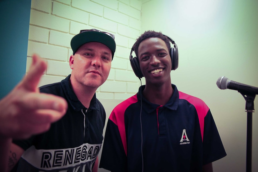 Scott Griffiths and Frank Mucho pose for a photo in a recoding studio with a pair of headphones on Frank's head.