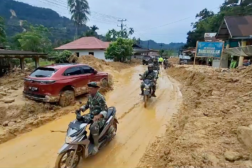 Soldiers in uniform ride motorbikes along muddied roads