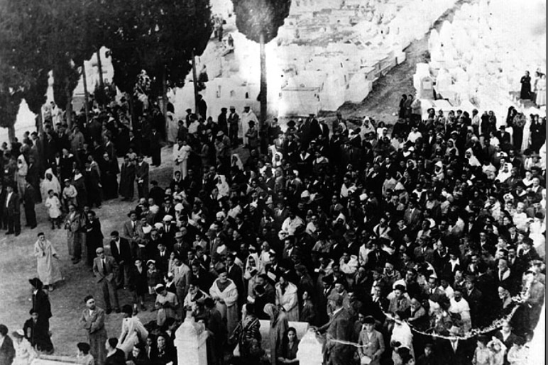 Black and white film image of Jewish men praying in a cemetery in Morocco in 1953