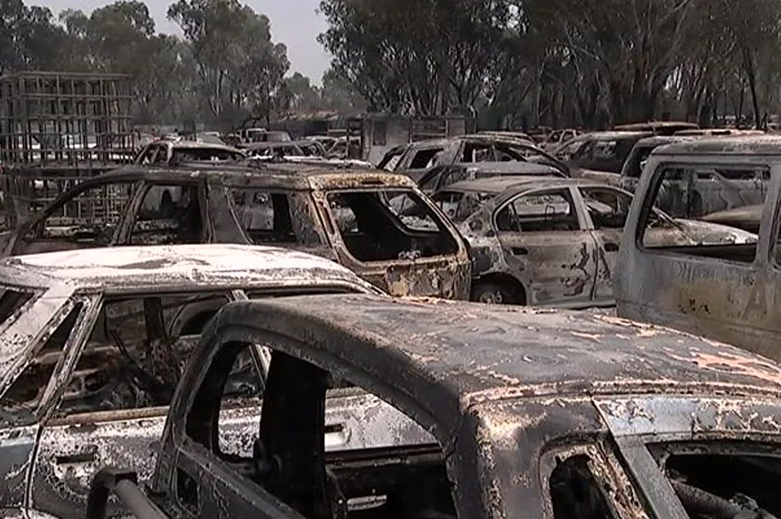 Badly burnt cars sit abandoned in a charred yard