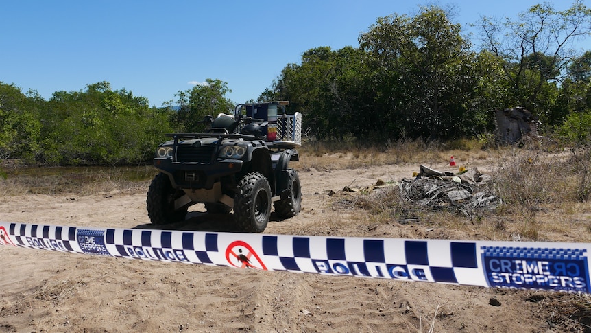 Police tape near a quad bike on a sandy track