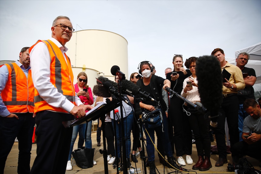 Media pack at a media conference with Anthony Albanese in high-vis vest answering questions.
