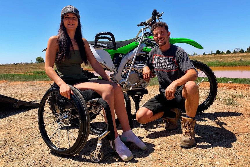 Chistina Vithoulkas in a wheelchair bext to partner James Wild with a modified two-wheeler bike behind them.