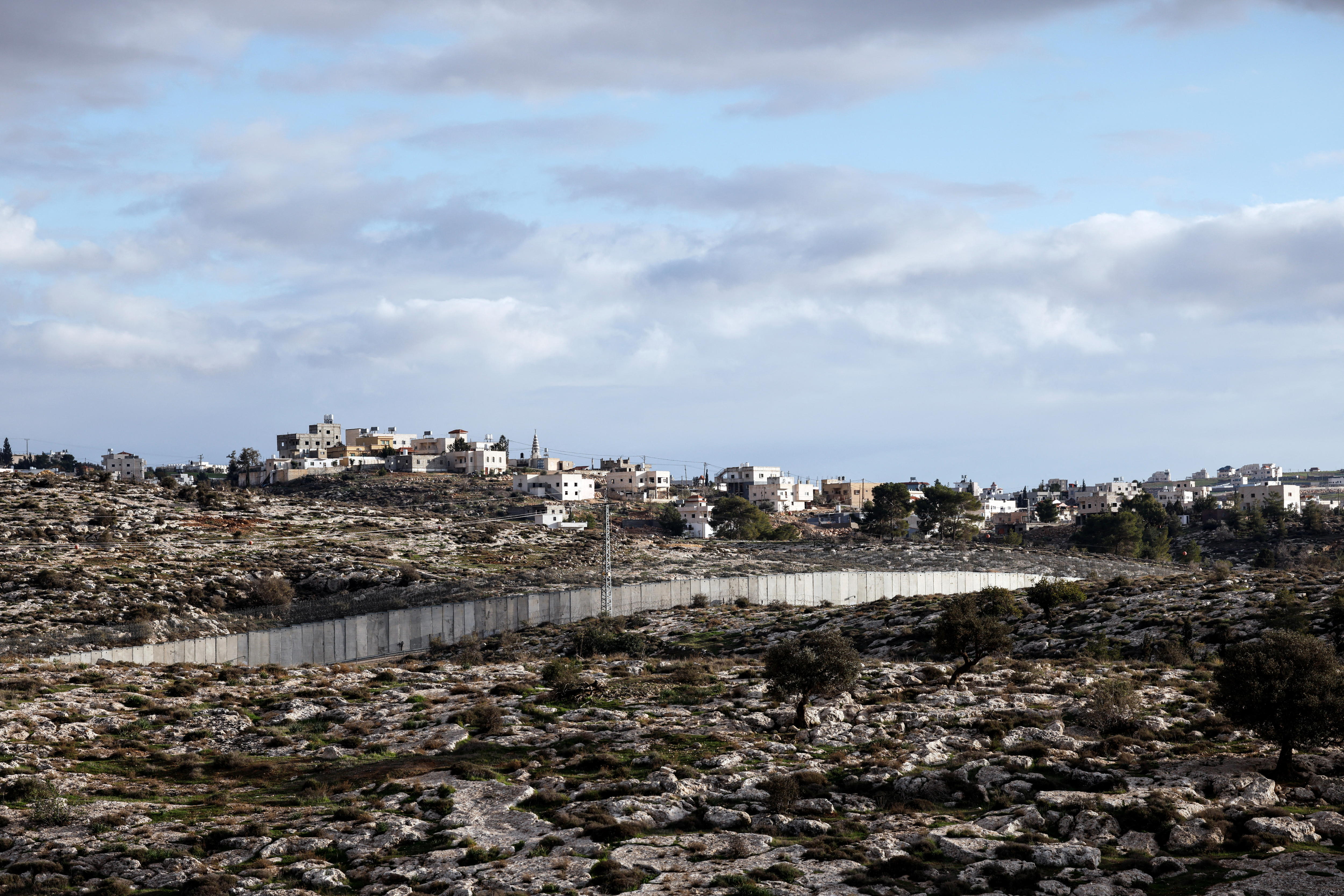 A concrete wall extends across a rocky hillside