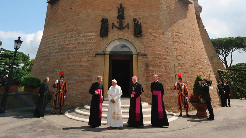 Pope Benedict XVI and several Bishops stand in wait in front of Saint John's Tower.