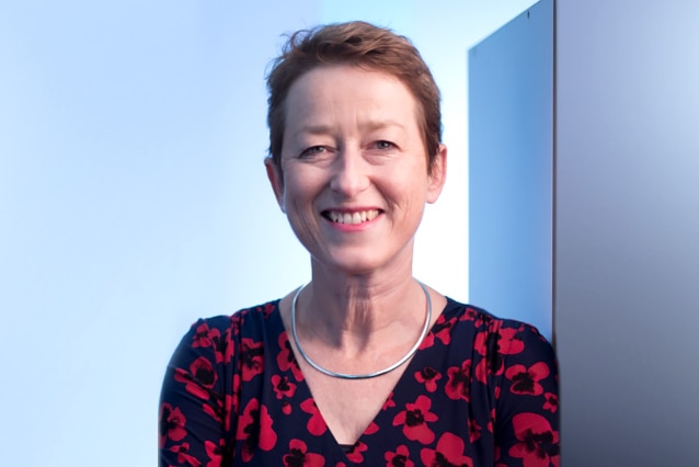 A photograph of Professor Lisa Gibbs wearing a black and red print shirt