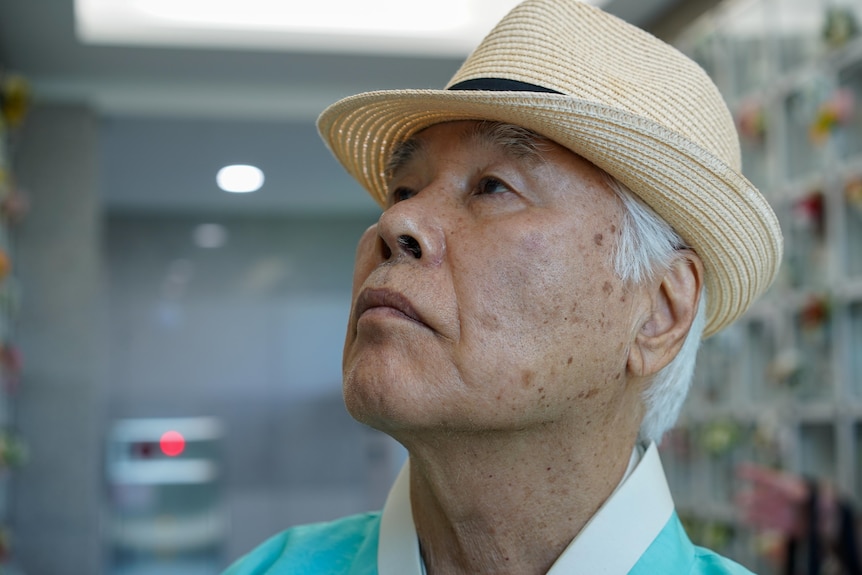 A close-up of Kim Young-hwan wearing a hat and with his head titled upwards.