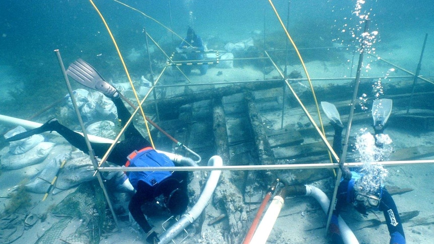 Three drivers underwater, examining the Sydney Cove shipwreck.