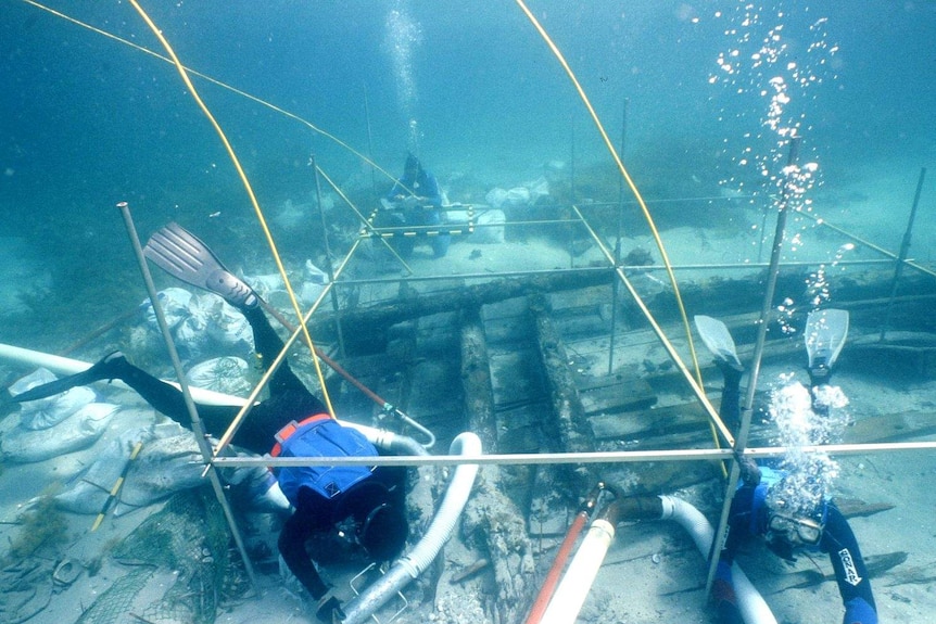 Three drivers underwater, examining the Sydney Cove shipwreck.