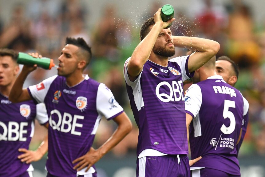 Perth Glory players drink from water bottles and spray water on themselves.