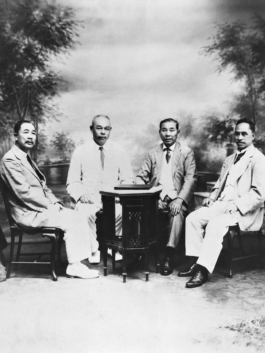 Four Chinese-Australian men dressed in business attire sitting around a table.