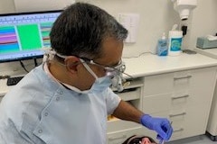 A dentist works on a patient in a surgery.