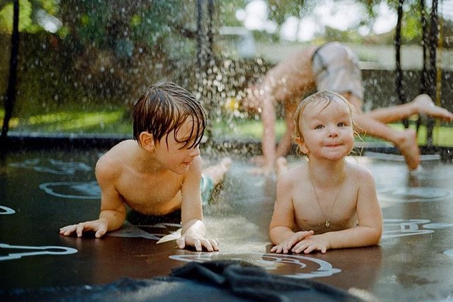 Two young children playing in shallow water.