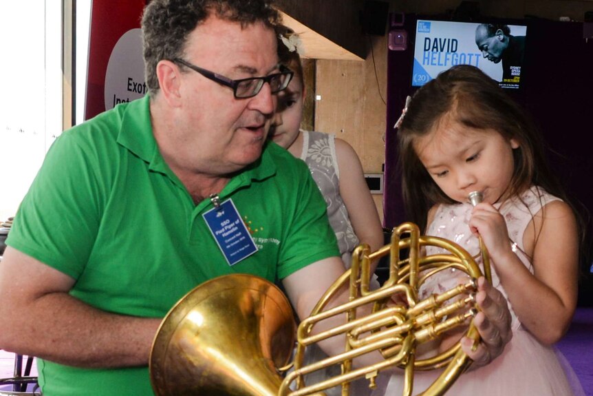 Little girl tries to play the French horn