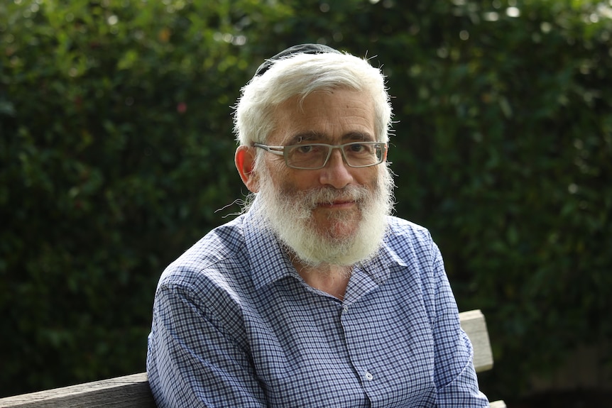 A man with a beard and wearing a yarmulke smiles at the camera.