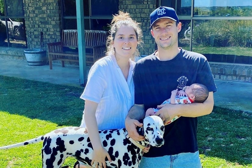 Couple holding newborn baby with dog.