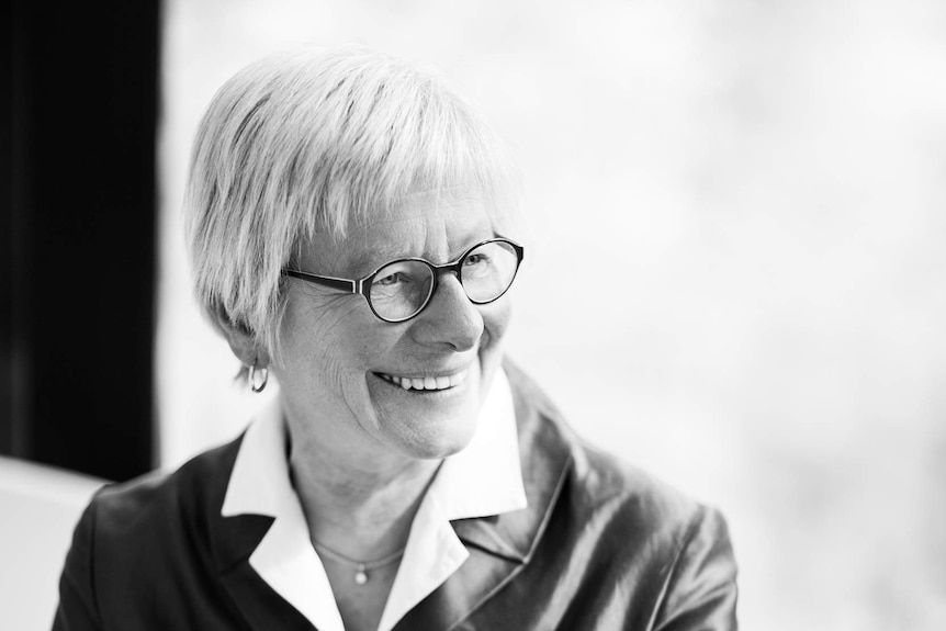 A woman with short, light-coloured hair smiles for a portrait