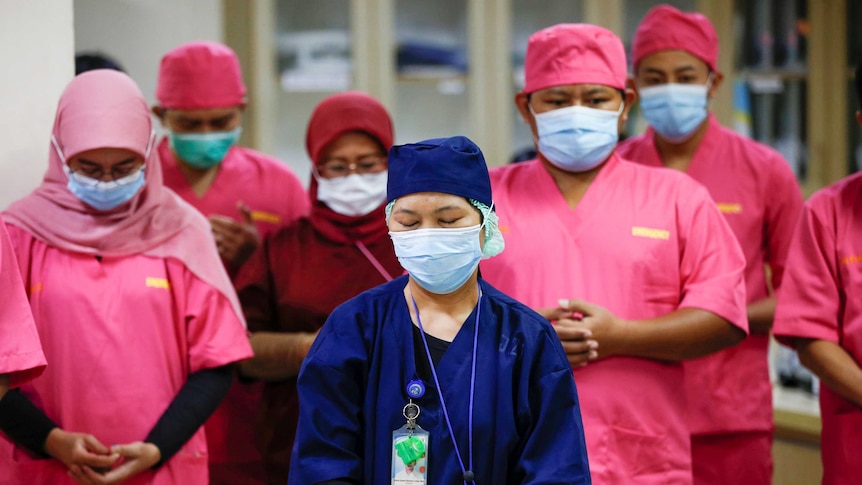 Healthcare workers wearing protective face masks pray for coronavirus disease patients.
