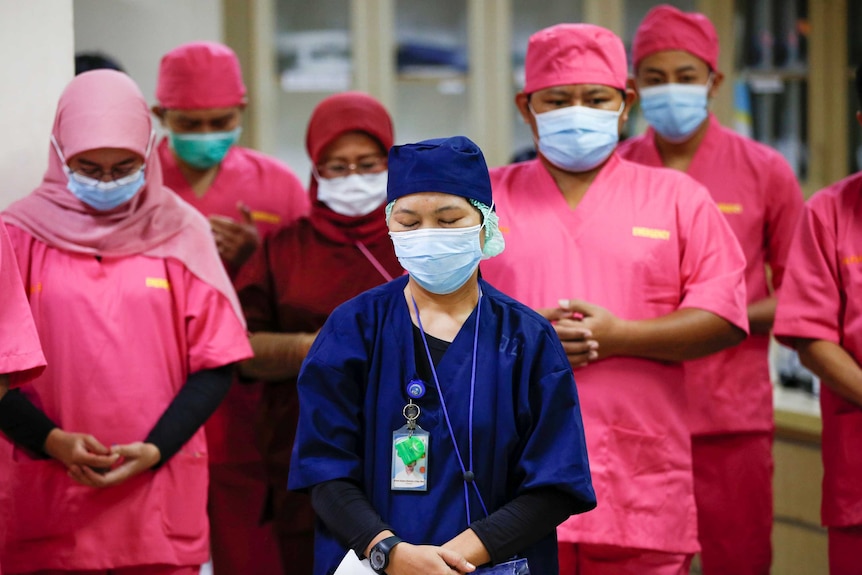 Healthcare workers wearing protective face masks pray for coronavirus disease patients.