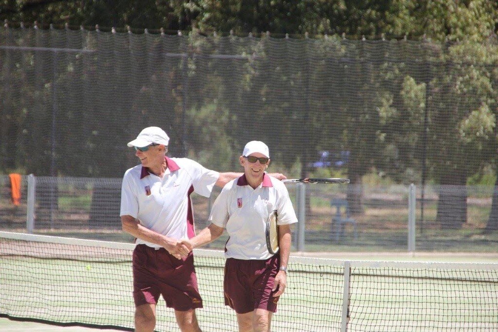two old men in white on tennis court