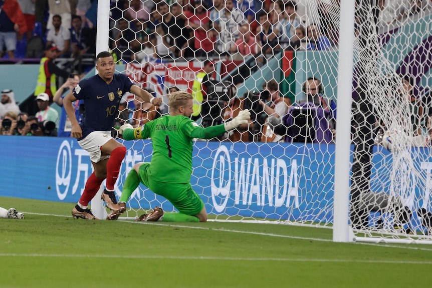 French striker Kylian Mbappe runs away from goal as a stranded Danish goalkeeper looks behind him to see the ball in the net.