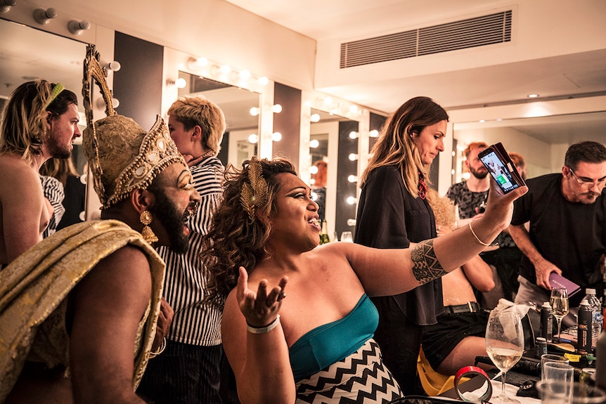 Colour photo of artists Shahmen Suku and Remedy Vaivaka posing with a mobile phone in dressing room.