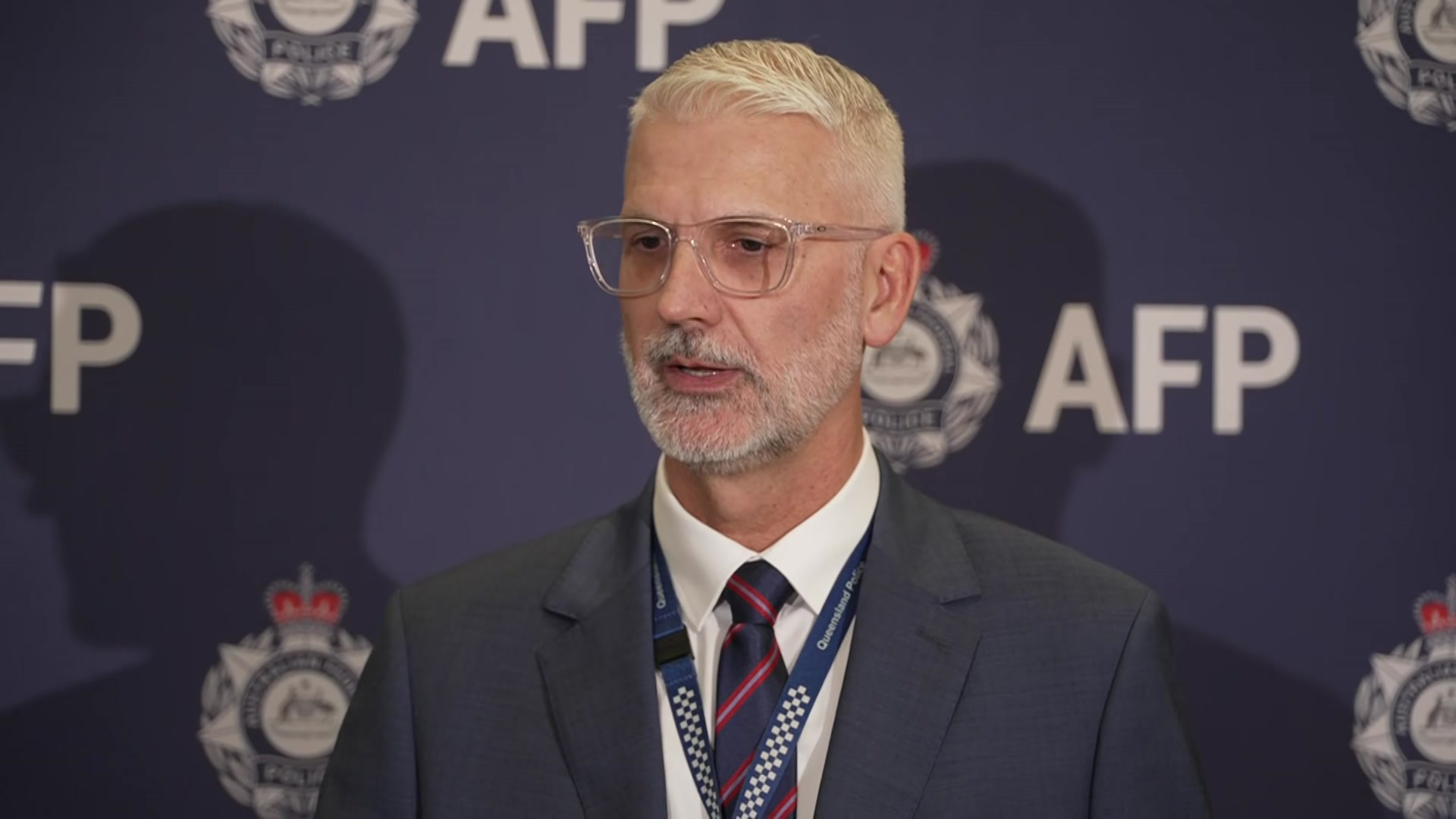 A policeman in a suit with grey hair and glasses.
