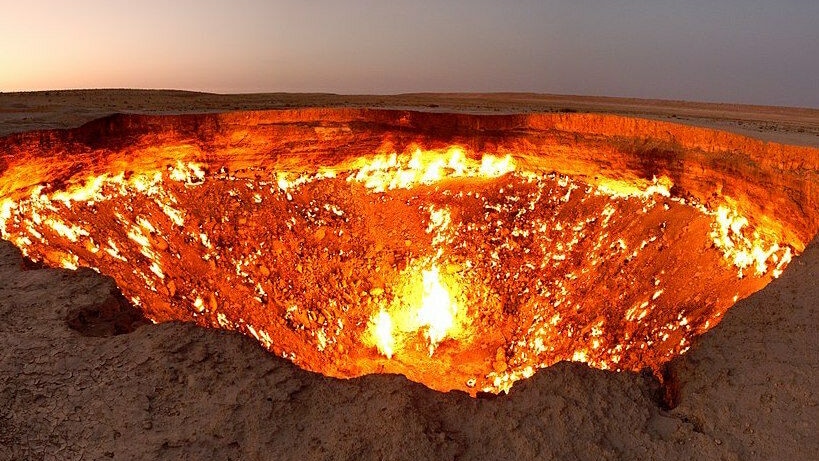 A burning round crator lies in the middle of the desert.