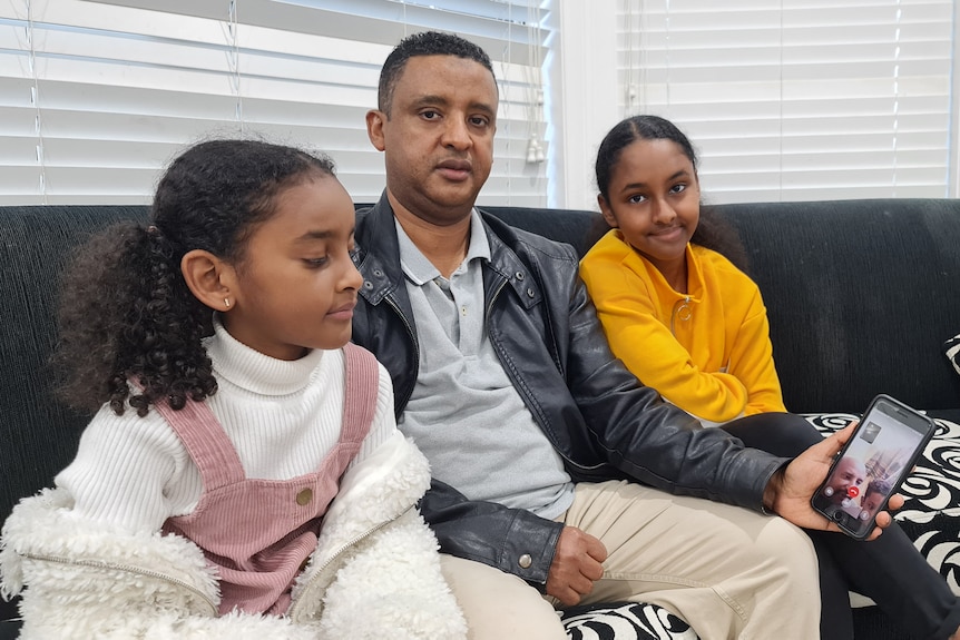 a man sitting on a couch with two young girls