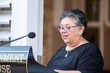 lady reading from a lectern into a microphone at an event